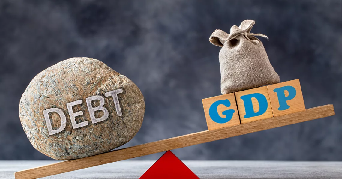 Debt-to-GDP ratio, a large stone with text DEBT and wooden cubes with GDP letters and bag on seesaw