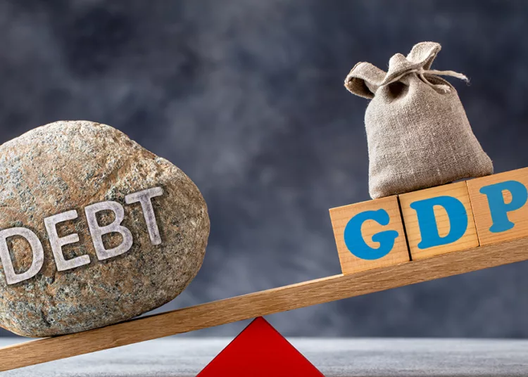 Debt-to-GDP ratio, a large stone with text DEBT and wooden cubes with GDP letters and bag on seesaw