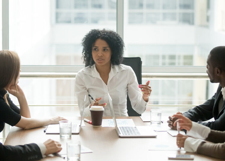 Black female boss leading corporate multiracial team meeting talking to diverse businesspeople, african american woman executive discussing project plan at group multi-ethnic briefing in boardroom